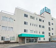 3階建ての介護施設の建物外観。緑色の庇が特徴的な玄関エントランス。